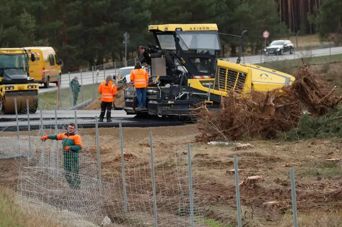 Workers are pictured along a construction road on the future site where US electric car giant Tesla is set to build his new car factory, in Gruenheide near Berlin, on February 17, 2019. - Tesla began clearing a 92-hectare (227-acre) area of forest at the site in Gruenheide in Brandenburg for its first European 