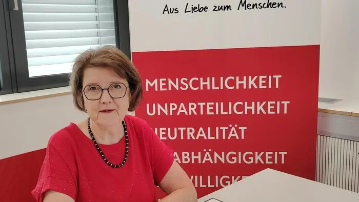 Eine Frau mit Brille und rotem Oberteil sitzt an einem Tisch
