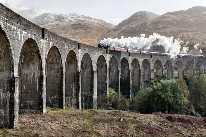 Beim Glenfinnan Viadukt zwischen Fort William und Mallaig im Westen von Schottland werfen Harry und Ron einen BLick aus dem Ford Anglia (Band 2 - Die Kammer des Schreckens) auf den Hogwarts Express. Von April bis Oktober 2019 kann man selbst mit dem Jacobite Steam Train fahren - er sieht dem Zauberzug verblüffend ähnlich.