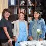 Drei Frauen stehen vor einem Tisch, Kaffeetassen und Bücher sind im Vorder- und Hintergrund | Stadtmarketing-Chefin Inga Horny, Sandwirth-Direktorin Johanna Glaser und Initiatorin Cornelia Hübner (von links) laden zum „Treffpunkt Lichtblicke“