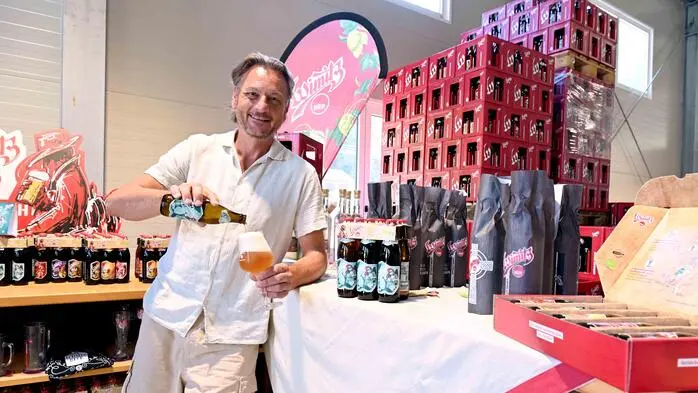 Ein Mann, sommerlich gekleidet, schenkt sich ein Glas Bier ein.
