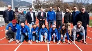 Mehrere Menschen haben sich auf einer Laufbahn positioniert und lächeln in die Kamera