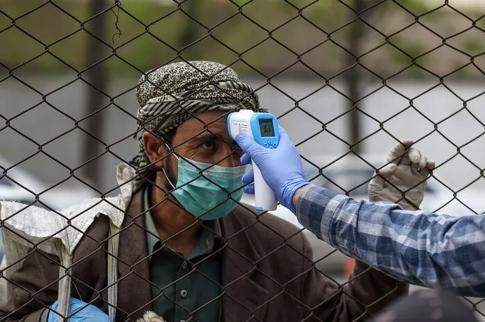 In Kabul wird die Körpertemperatur von Gläubigen vor dem Betreten der Akbar Khan-Moschee von Mitarbeitern des Gesundheitsministeriums überprüft.  