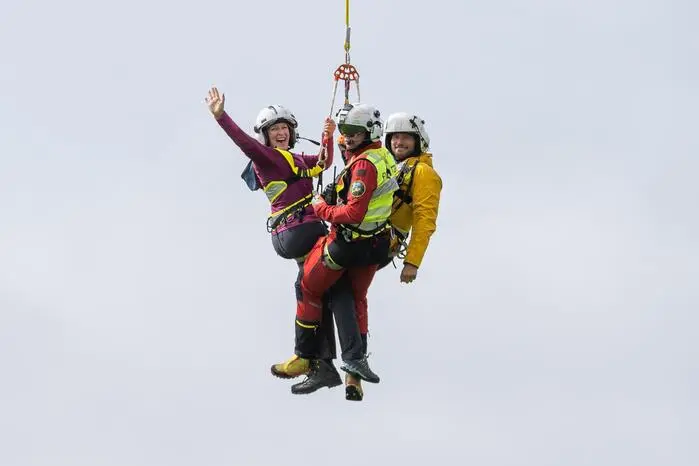 Die Schauspielerin Stefanie von Poser (l.) und ihr Kollege Sebastian Ströbel (r.) wurden am Ziel der Wanderung, dem  Pernerhof alias „Hof Emilie“, am Tau hängend eingeflogen, in der Mitte ein Flugretter