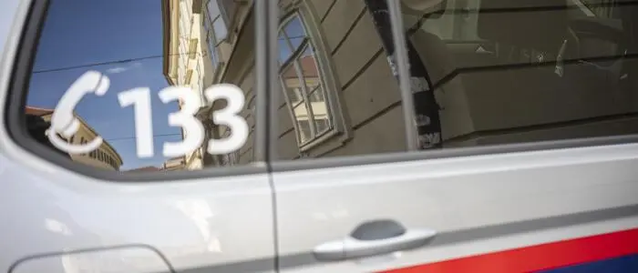 Detailaufnahme eines Polizeiautos, das in der Nähe des Tatorts geparkt war. Im Fenster spiegeln sich historische Bauten in der Grazer Innenstadt