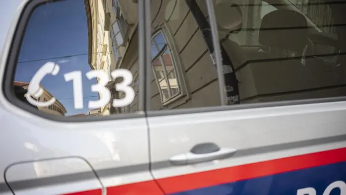 Detailaufnahme eines Polizeiautos, das in der Nähe des Tatorts geparkt war. Im Fenster spiegeln sich historische Bauten in der Grazer Innenstadt