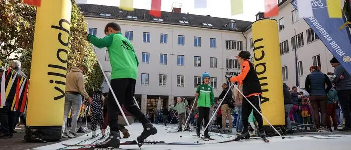 Mehrere Jugendliche testen Langlaufski auf einem Platz in der Innenstadt