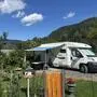 Ein Camper steht an einem sonnigen Tag auf einer Wiese
