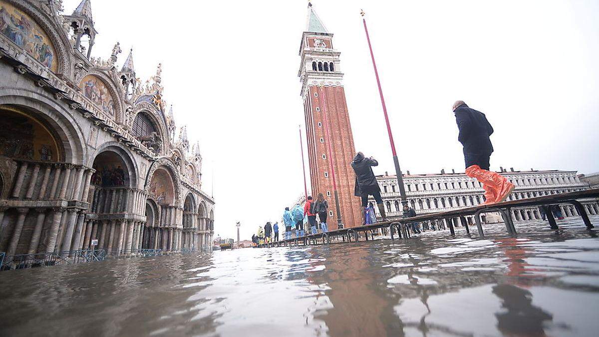 Auf Stegen überqueren Touristen den Markusplatz