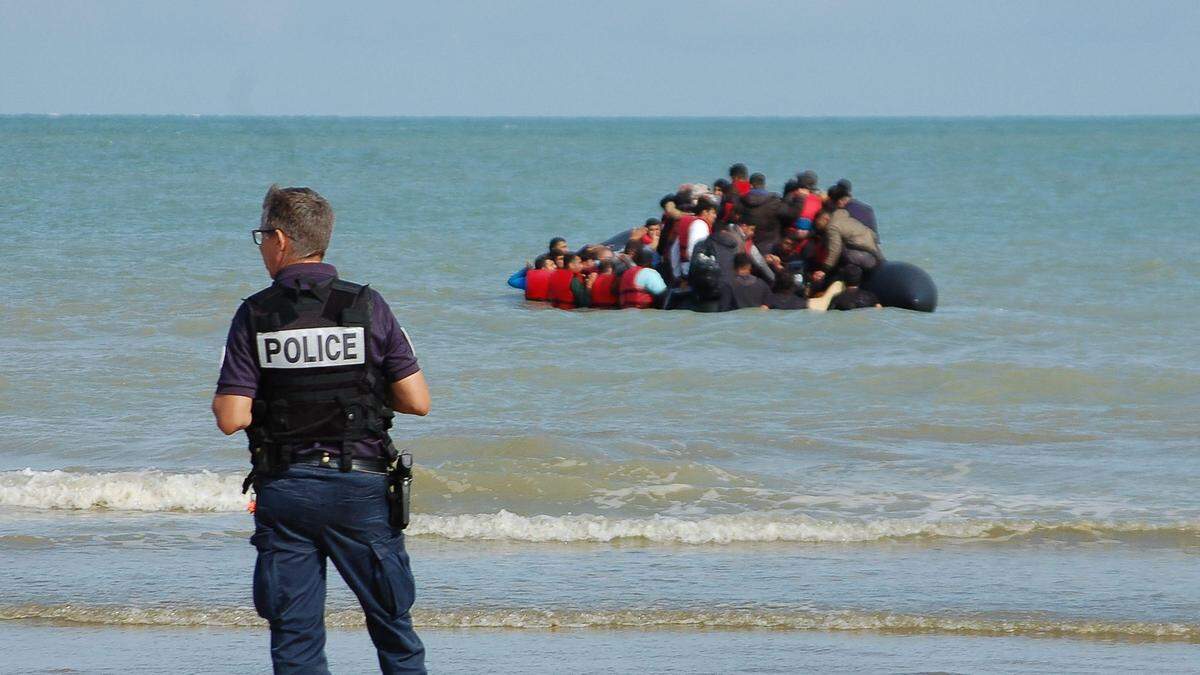 Ein Polizist vor einem Schlauchboot mit Flüchtlingen | 2022 kamen 46.000 Menschen illegal an den Küsten Großbritanniens an 