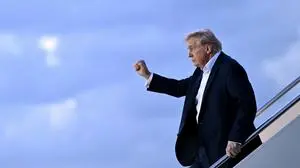 US President Donald Trump raises a fist as he steps off Air Force One at Palm Beach International Airport in West Palm Beach, Florida, on April 11, 2025. Trump is heading to Palm Beach to spend the weekend at his Mar-a-Lago resort. (Photo by Mandel NGAN / AFP)