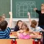 Kinder in einer Schulklasse zeigen auf, Lehererin an der Tafel | Trotz Veränderungen: Musikschwerpunkt soll wertvoller Teil der Lavanttaler Bildungslandschaft bleiben
