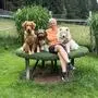 Eine Frau sitzt mit drei Hunden auf einem Hocker