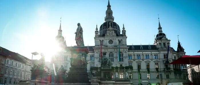 Blick auf das Grazer Rathaus, über das Dach strahlt die Sonne hervor
