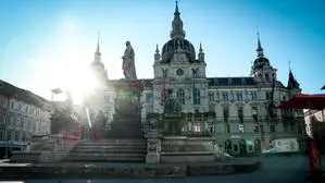 Blick auf das Grazer Rathaus, über das Dach strahlt die Sonne hervor