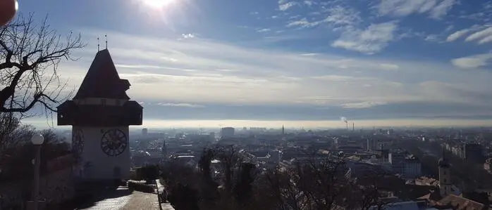 Das Bild zeigt den Blick über Graz vom Uhrturm aus. Die Sonne steht tief.