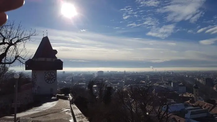 Das Bild zeigt den Blick über Graz vom Uhrturm aus. Die Sonne steht tief.
