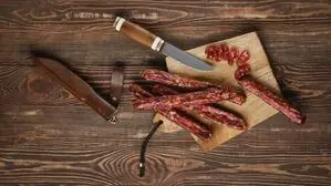 Hartwürste auf einem Holzbrett mit einem Messer