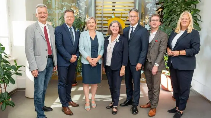 Die neue Grazer Stadtregierung nimmt Aufstellung: Manfred Eber, René Apfelknab, Judith Schwentner, Elke Kahr, Kurt Hohensinner, Robert Krotzer, Claudia Unger posieren nebeneinander stehend für den Fotografen vor der Tür im Bürgermeisterinnenamt