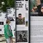 A woman visits the photo exhibition "The war is not over" opened in the Taras Shevchenko park in Kyiv on June 23, 2022, amid Russia invasion of Ukraine. (Photo by Genya SAVILOV / AFP)