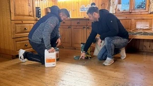 Zwei Männer knien am Boden und inspizieren diesen | Markus Ladinig (Geschäftsleiter Schatz Böden, rechts) und Mitarbeiter Dario Vidovic beim Inspizieren der nicht unerheblichen Bodenbelagsschäden im „Forsthaus“