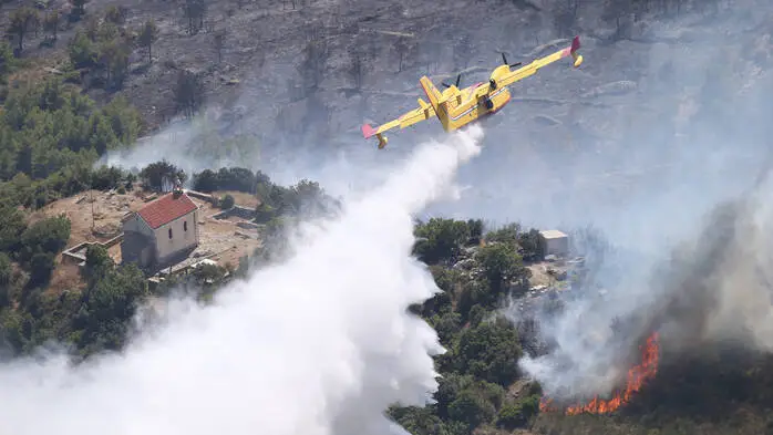 Ein Löschflugzeug versprüht Löschwasser über einem Waldbrand