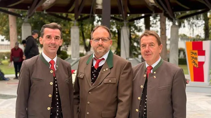 Drei Politiker blicken in die Kamera. Sie haben traditionelles Kärntner Gewand an.