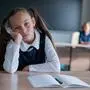 Little caucasian girl is bored at the lesson at school. The schoolgirl is sitting at her desk and the teacher is sitting in the background. Little caucasian girl is bored at the lesson at school. The schoolgirl is sitting at her desk and the teacher is sitting in the background Copyright: x RECORD DATE NOT STATED