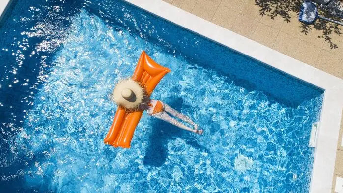 Eine Frau liegt im Pool auf einer Luftmatratze 