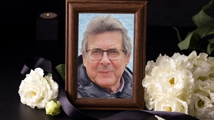 Ein gerahmtes Porträtbild des Verstorbenen inmitten von weißen Blumen