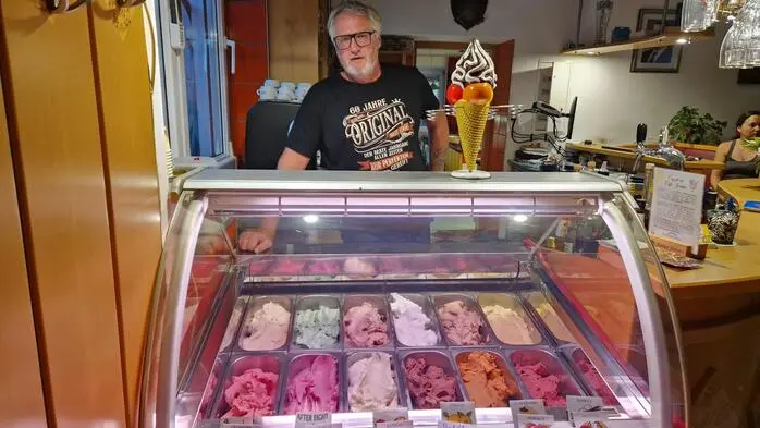 Ein älterer Herr steht hinter einer Eisvitrine