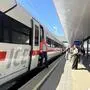 Ein ICE-Zug hält im Bahnhof, ein Schaffner tritt gerade aus der Tür. Am Bahnsteig warten Passagiere | Viel mehr Urlauber werden in Zukunft mit der Bahn in die Region reisen