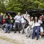 Man sieht viele junge Erwachsene vor ihren Autos jubeln