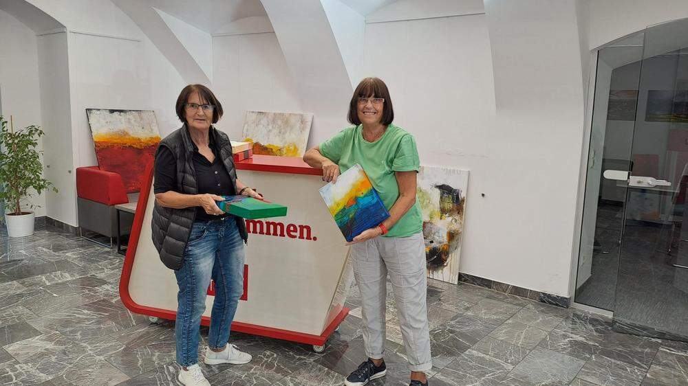 Die Feldbacher Künstlerin Herta Haas (r.) mit Anni Edelsbrunner (l.) bei der Montage der Werke im Regionalbüro der Kleinen Zeitung