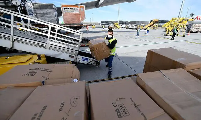 ABD0139_20200330 - SCHWECHAT - ÖSTERREICH: ZU APA0523 VOM 30.3.2020 - Ein Mitarbeiter des Flughafens beim Entladen von Schutzausrüstung am Montag, 30. März 2020, am Flughafen Wien-Schwechat. Die Austrian Airlines haben mit zwei zu Frachtflugzeugen umfunktionierten Boeing 777 weitere 30 Tonnen Schutzausrüstung aus China nach Österreich geflogen. Es handelte sich um knapp zwölf Tonnen Masken und knapp 18 Tonnen Mäntel. - FOTO: APA/HELMUT FOHRINGER