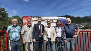 Sechs Männer stehen auf einer rot gestrichenen Brücke 