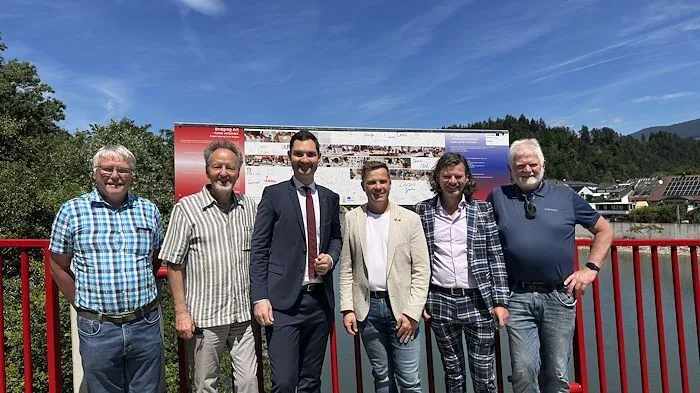 Sechs Männer stehen auf einer rot gestrichenen Brücke 