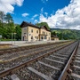Zu sehen ist ein Bahngleis und dahinter ein kleiner Bahnhof.