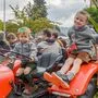 Zwei kleine Kinder sitzen auf einem alten, roten, geschmückten Traktor | Zwei Kinder auf einem Traktor freuen sich auf Erntedank