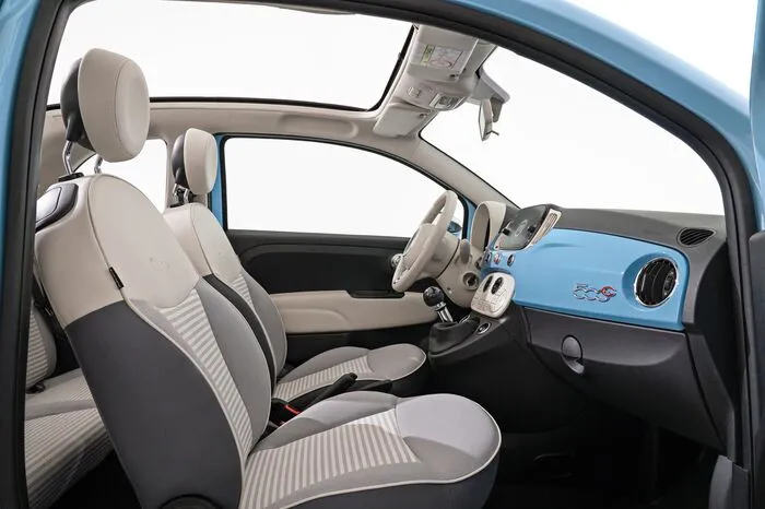Auch die Armaturenbretteinlage kommt in Himmelblau daher, die zweifarbigen Sitzbezüge in Grau gestreift im unterem Bereich und elfenbeinfarben Oberteil, das Lenkrad mit historischem Markenlogo sowie spezifische Fußmatten.