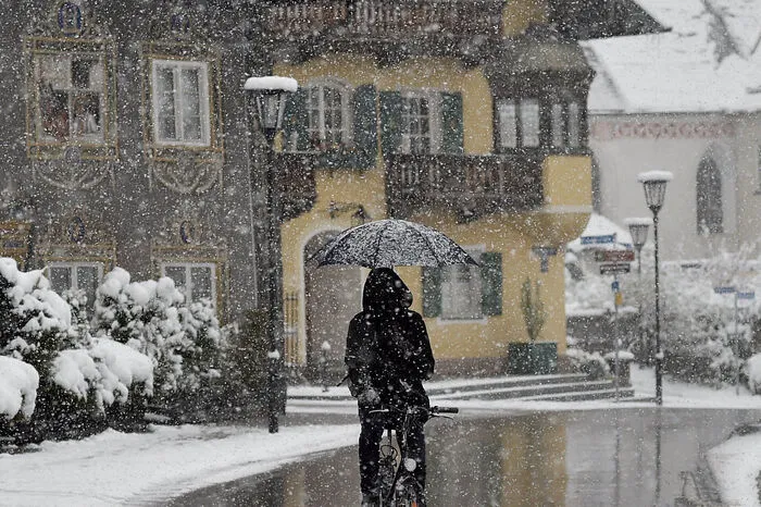 Ein Radfahrer fährt bei leichtem Schneefall durch Garmisch-Partenkirchen.