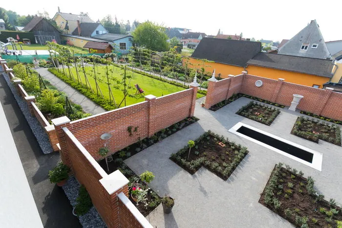 Die Ziegelmauer bildet die Trennung zwischen dem großen Garten mit dem Lindenspalier und dem Rosengartenraum.