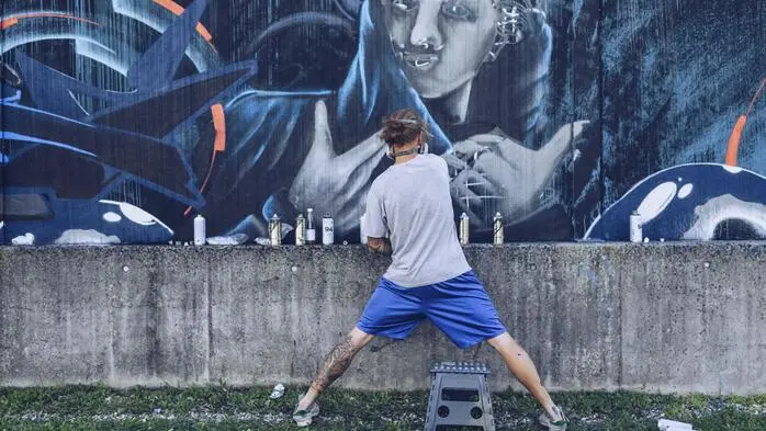 Ein Mann sprüht Graffiti auf eine Wand