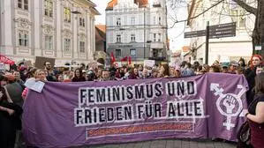 Foto von der Demo zum 8. März 2025 in Graz: „Feminismus und Frieden für alle“ ist auf dem Transparent mit einem Gender- und Protestsymbol zu lesen
