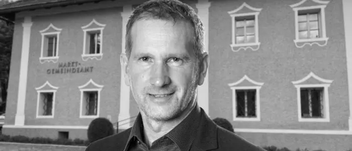 Schwarz-Weiß Montage: Ein Mann steht vor einem Gemeindeamt