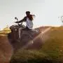 A sexy girl with long dark hair rides an ATV off-road; the girl feels drive and adrenaline; extreme recreation outside the city; Quad bike rental