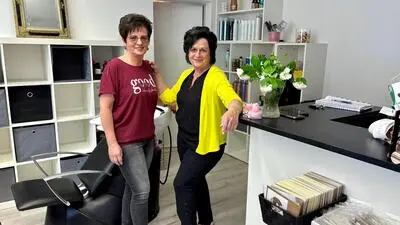 Mitarbeiterin Veronika Findenig und Inhaberin Sissy Adam in ihrem Friseursalon. Über die Tür im Hintergrund gelangt man vom Salon aus in den Verkaufsraum mit den Lebensmitteln
