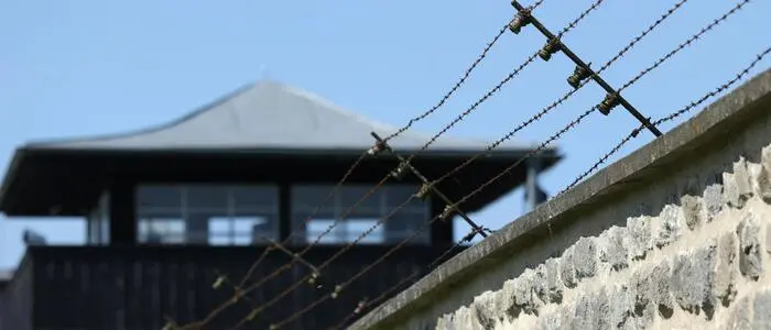 Im Bild: Einer der Wachtürme und ein Teil der Mauer mit Stacheldraht der KZ-Gedenkstätte Mauthausen