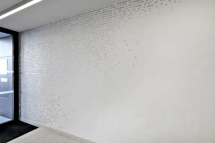 „PATTERN_WGS_05“ von Claus Prokop beim Projekt in der  Gumpendorfer Straße 123: Eine lange Wand im Eingangsbereich wurde als ein aus unzähligen Teilchen bestehendes Motiv entwickelt, das sich zu den Rändern hin dynamisch auflöst...