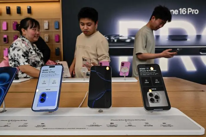 People browse for Iphone 16 displayed in a Apple store in the Huangpu district in Shanghai on April 11, 2025. US President Donald Trump abruptly paused tariffs on most countries, sparking euphoria on global markets on April 10, but upped the ante on a brutal trade war with superpower rival China. (Photo by Hector RETAMAL / AFP)